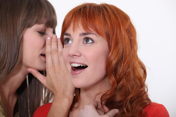 Woman whispering into another woman's ear