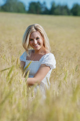 Fototapeta premium Beautiful happy woman smiles in wheat field