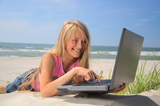 Smiling young woman using laptop on beach