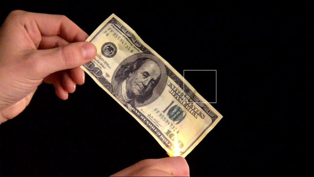 Burning dollars in the hands of men. close-up