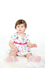 The little girl in an elegant dress sits on a floor