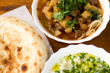 Close up of soup lagman decorated with greens and lavash