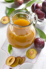 Plum juice and fresh fruits with leaves