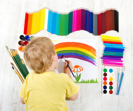 Child painting picture with brush in album using a lot of painti