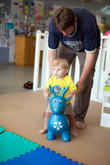 Young father playing with his son in kindergarten