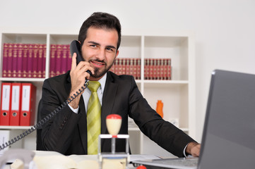 Junger Geschäftsmann im Büro telefoniert