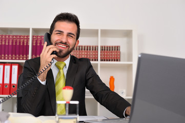 Junger Geschäftsmann im Büro telefoniert mit einem Kunden