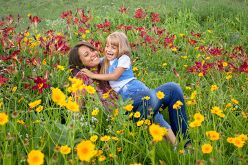 Happy mother and daughter lying in flowers