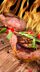 Delicious beef steaks with flames on background