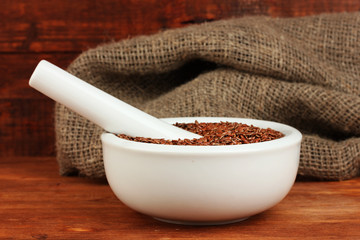 Mortar with flax seeds on wooden background close-up