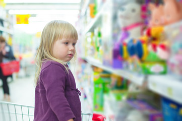 Adorable baby with toys on shelves in mall