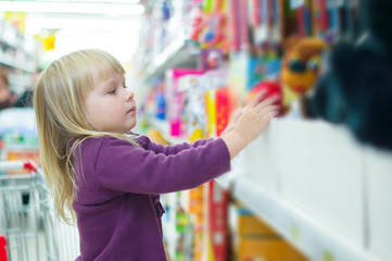Adorable baby with toys on shelves in mall