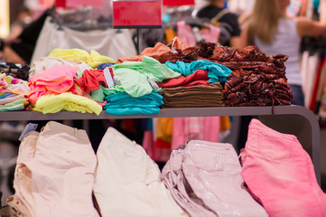 Variety of color t-shirts and jeanses on table in mall