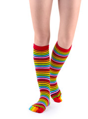 female legs in colorful striped socks isolated on white