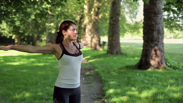 Young attractive woman stretching, exercising in the park