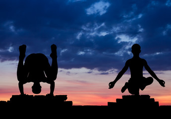 Silhouette in yoga pose on a brick wall.