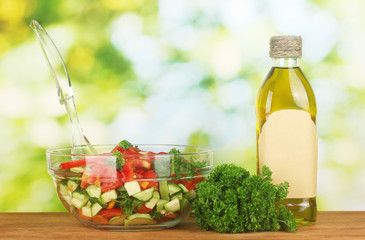 Fresh salad and oil on green background
