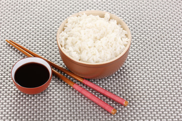 Bowl of rice and chopsticks on grey mat