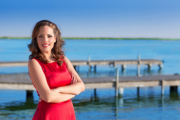 Brunette woman dress in red smiling relaxed on a lake