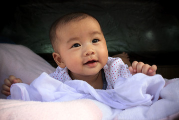 Naklejka premium asian baby smiling face lied on bed