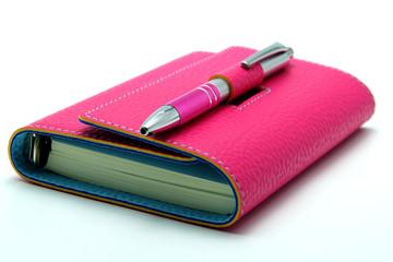 Personal Organizer in Pink Color With Ballpoint Pen on White Bac