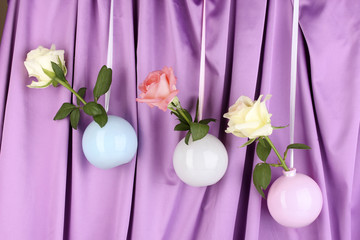 Fototapeta na wymiar Beautiful roses in vases hanging on cloth background