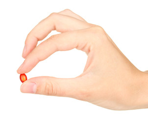 Woman's hand holding a red pill on white background close-up