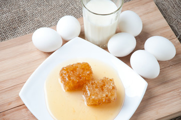 Fresh honey, glass of milk and chicken eggs, studio shot