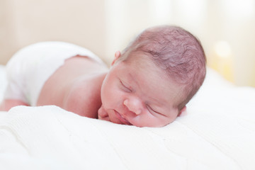  fortnight newborn baby in a diaper sleeps, lying on a stomach