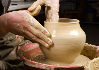 hands of a potter, creating an earthen jar of white clay