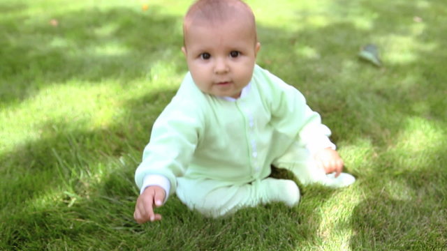Happy small boy sitting on the green grass