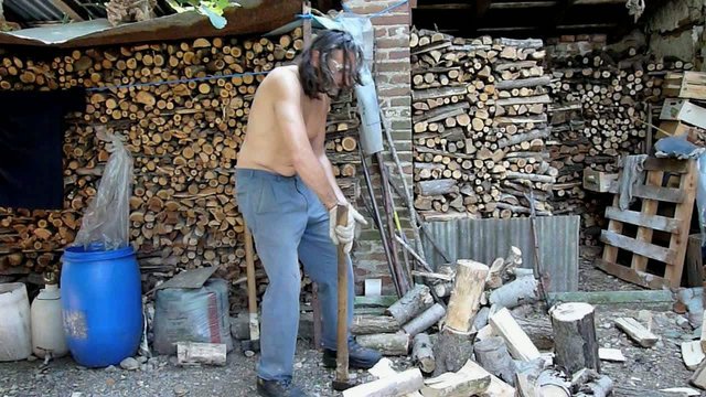 shirtless man chopping wood