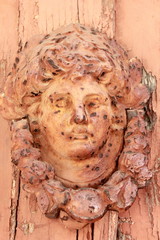 woman head and face door knocker with flaky peeling paint and distressed wood 