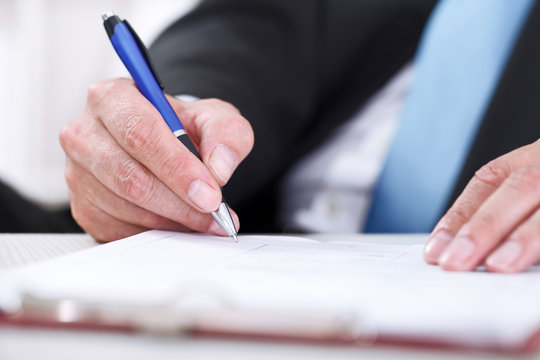 Close up of businessman signing a contract.