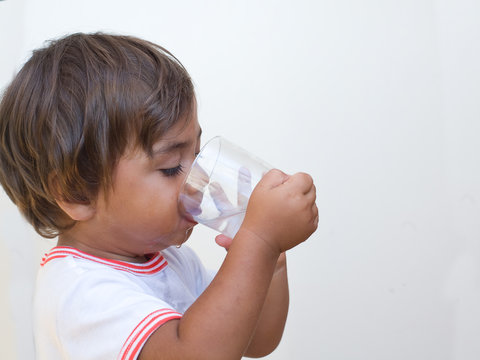 Foto Stock bambino beve acqua dal bicchiere | Adobe Stock