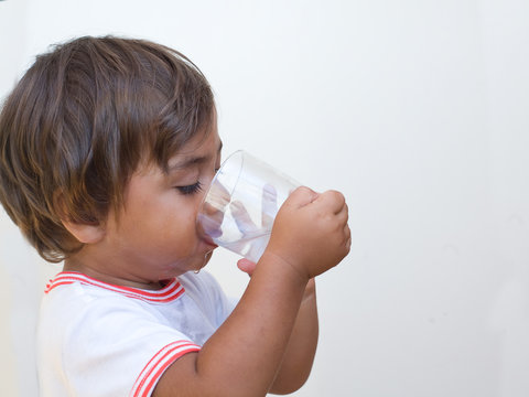 bambino beve acqua dal bicchiere