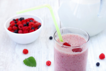Raspberry and blueberry milkshake on white wooden table