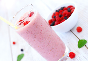 Raspberry and blueberry milkshake on white wooden table
