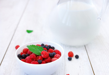 Ceramic white bowl filled with fresh raspberries and blueberries