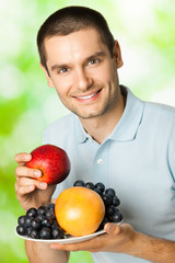 Obraz premium Happy smiling man with plate of fruits, outdoors