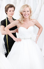 Naklejka premium Seamstress tightens up the corset of the wedding gown