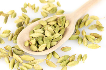 green cardamom in wooden spoon on white background close-up
