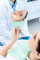The patient admires her smile looking at the mirror