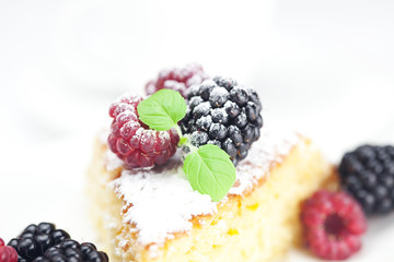 cake with icing, raspberry, blackberry and mint  on a white back