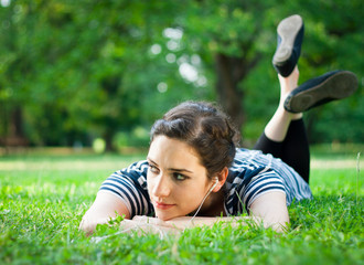 Young woman relaxing and listening to music outdoors