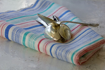 Some teaspoons on colourful kitchen towel on metallic surface