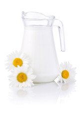 Obraz na płótnie Canvas Jug świeżego mleka i trzy kwiaty rumianku na białym bac