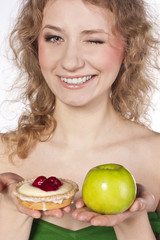 Beautiful blonde choosing, between an apple and a cake