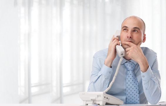 Businessman Talking On Landline Phone At Office