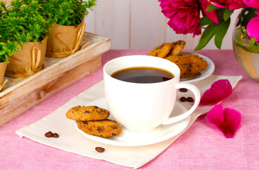 cup of coffee, cookies and flowers on table in cafe
